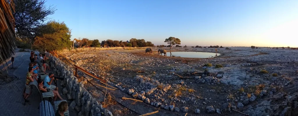 Visitors sit beside the Okaukuejo waterhole viewing area.