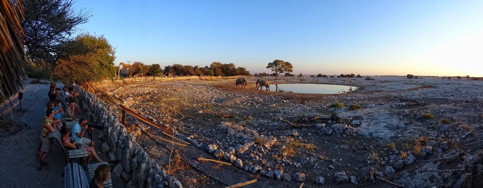 Visitors sit beside the Okaukuejo waterhole viewing area.